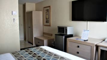 A hotel room with a bed, a desk, a television, a microwave, and a wardrobe.