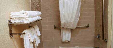 A bathroom with a bathtub, a shower curtain, and a towel rack with folded towels.