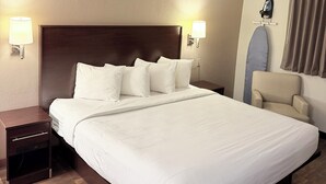 Ein Hotelzimmer mit einem großen Bett, Nachttischen, einem Sessel und einem an der Decke befestigten Bügeleisen.