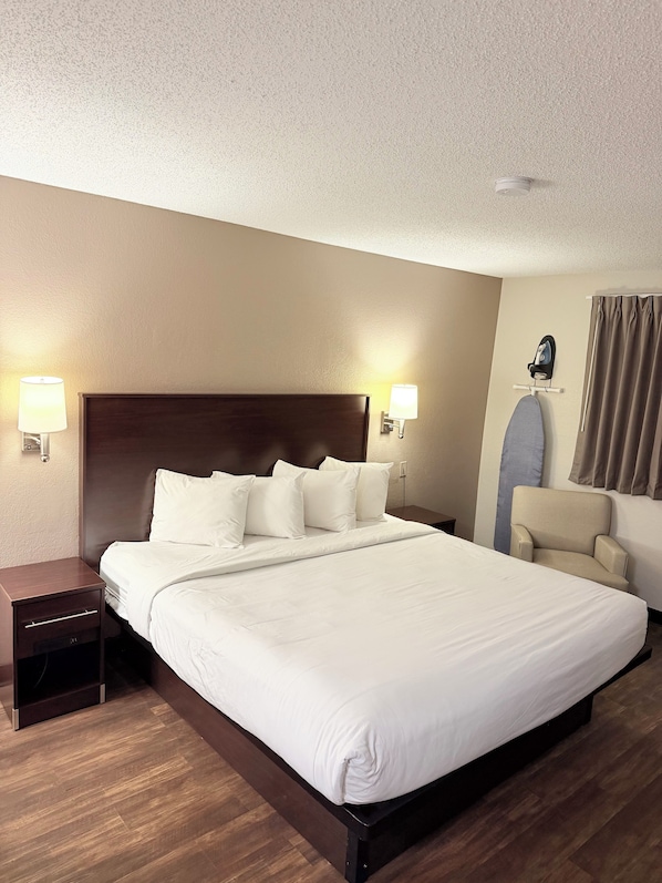 A hotel room with a large bed, bedside tables, a chair, and a ceiling-mounted iron.