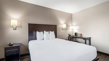 A hotel room with a large bed, bedside tables, a desk, and wall-mounted lamps.