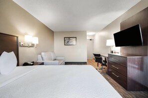 A hotel room with a bed, a desk, a chair, a TV, and a wall-mounted lamp. - Baymont by Wyndham Findlay (Findlay)