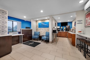 Un hall de hotel con mostrador de recepción, zona de estar y kitchenette.