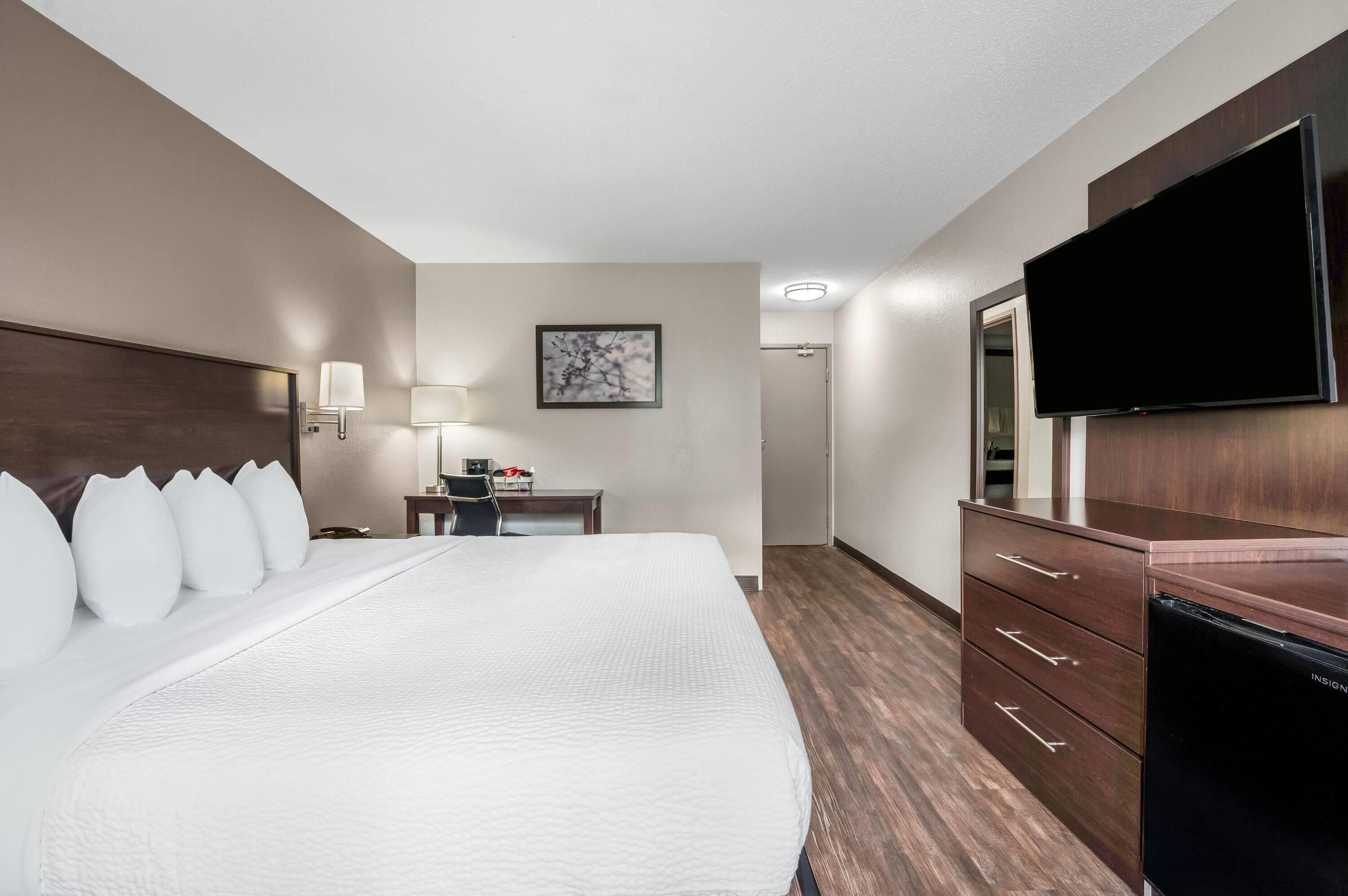 Habitación de hotel con una cama grande, un escritorio con lámpara, un televisor de pantalla plana y un aparador.