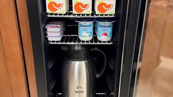 A beverage vending machine with apple and orange juice, Dannon nonfat yogurt, and a milk dispenser.