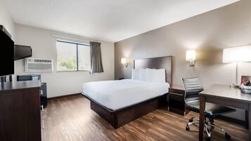 Una habitación de hotel con cama, escritorio, silla y televisión.