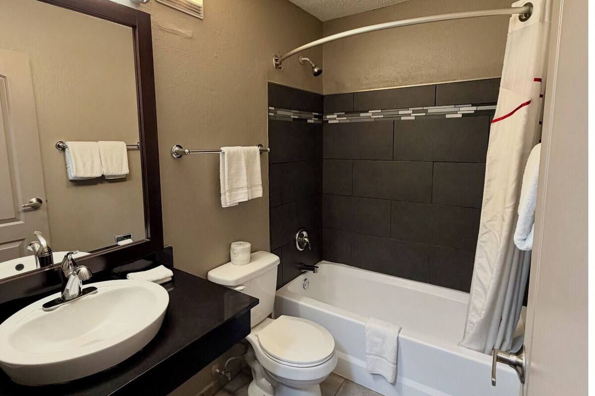 A modern bathroom with a sink, toilet, and bathtub.