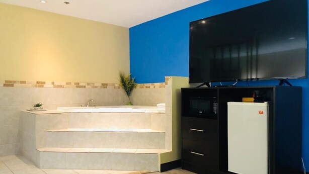 Ein modernes Badezimmer mit einer Badewanne, einem Waschbecken und einem an der Wand befestigten Fernseher.