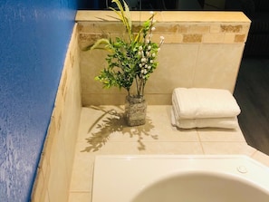 A bathroom with a bathtub, a white towel, and a vase with flowers.