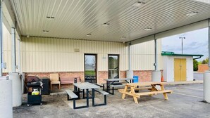 Ein überdachter Außenbereich mit Picknicktischen und einem Grill.
