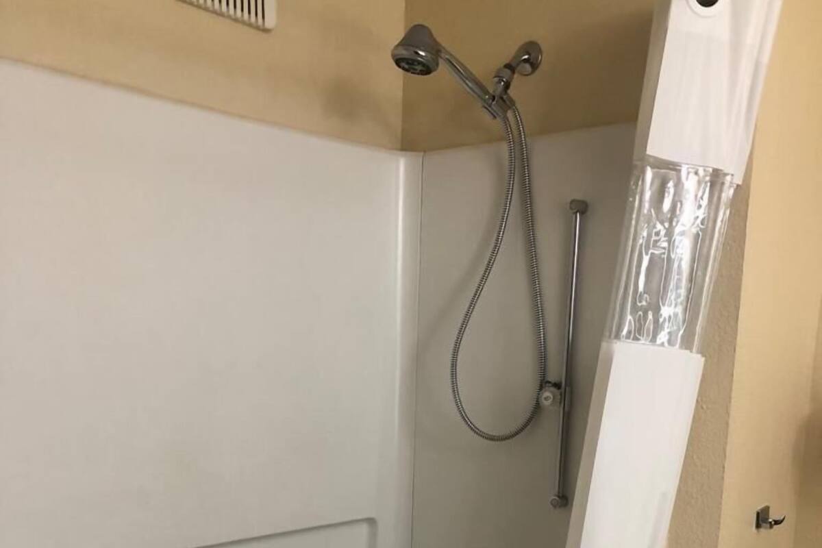 A walk-in shower with a handheld showerhead, a handheld showerhead, and a shower curtain.