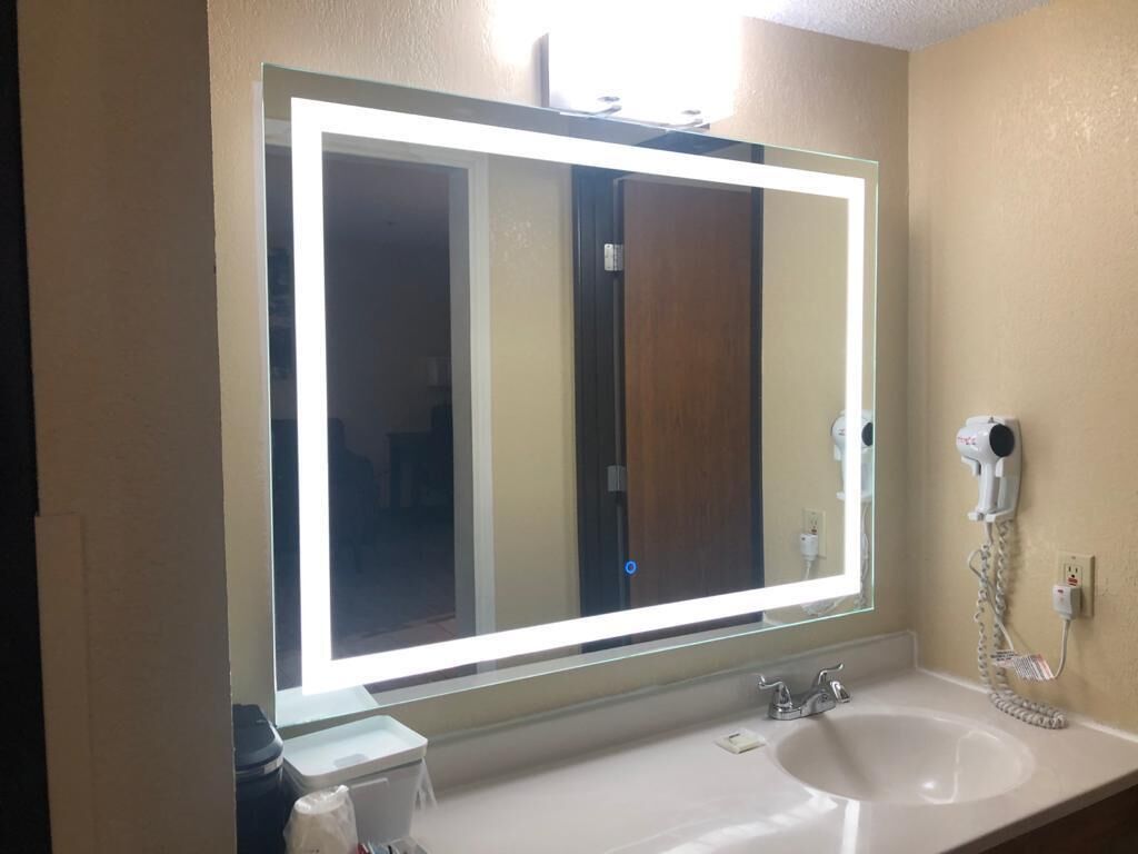 Un baño con un espejo grande, un lavamanos y un secador de pelo en la pared.
