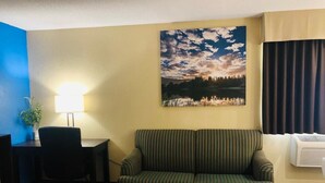 Ein Wohnzimmer mit einer Couch, einem Couchtisch, einer Lampe und einem Landschaftsbild.