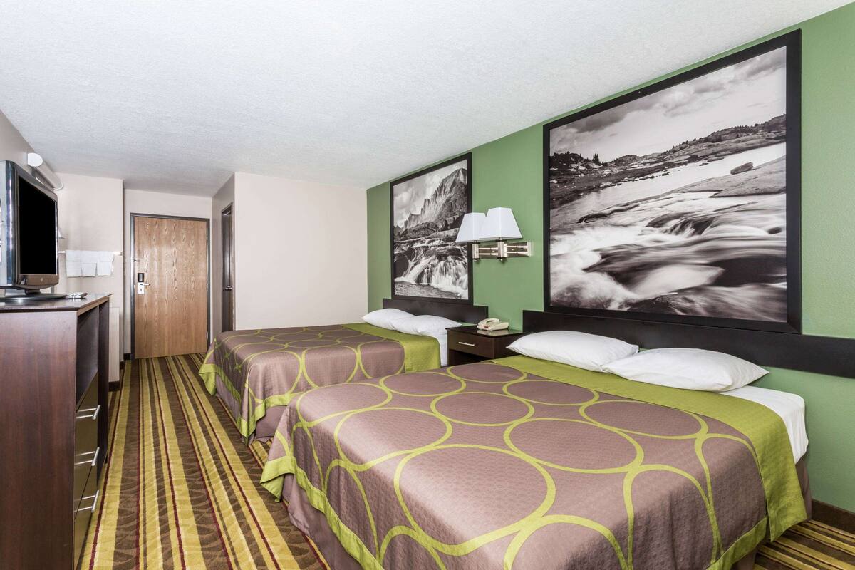 Een hotelkamer met twee bedden, een bureau en een televisie.