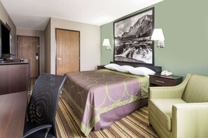 Ein Hotelzimmer mit Bett, Schreibtisch, Stuhl, Nachttisch und einer Wandlampe.