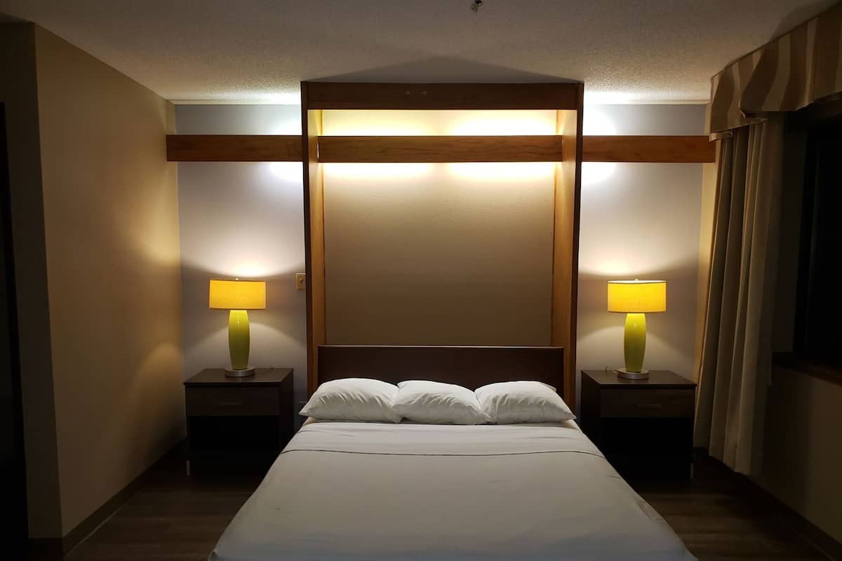 A hotel room with a large bed, two bedside tables with lamps, and a wooden headboard.