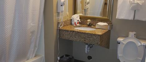 A bathroom with a shower, toilet, sink, and a mirror.