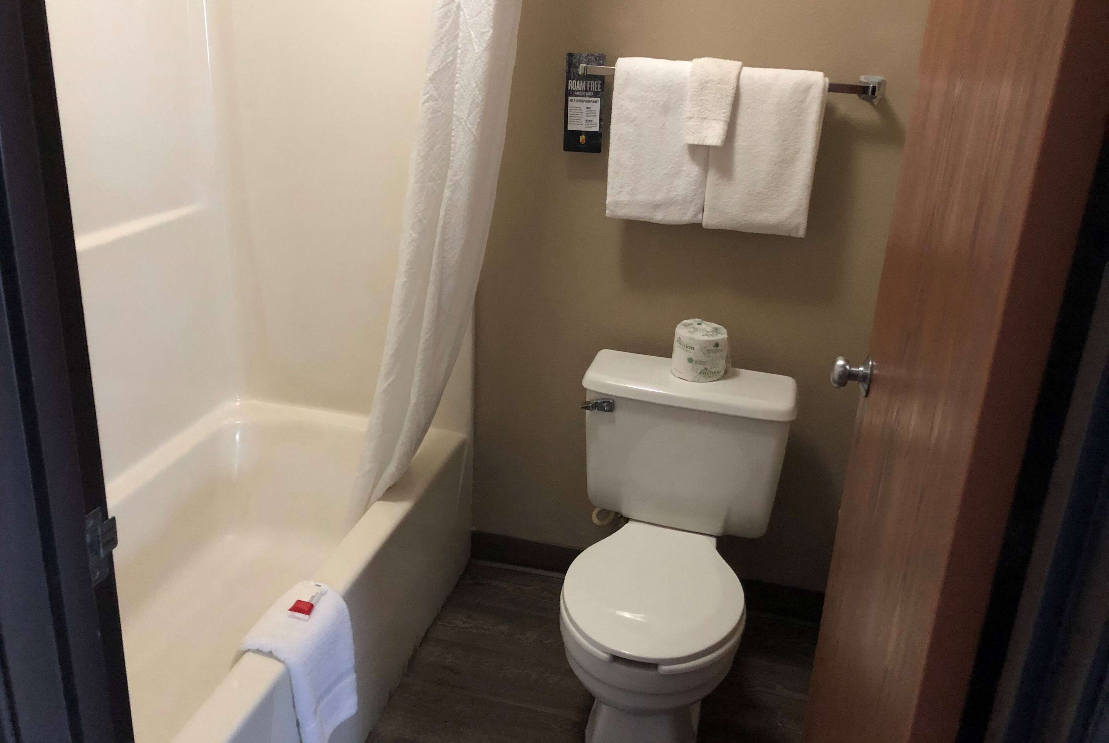 Un baño con bañera, inodoro y un perchero con dos toallas.