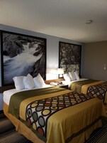 Habitación de hotel con dos camas, una mesita de noche, una lámpara y dos grandes obras de arte en la pared.