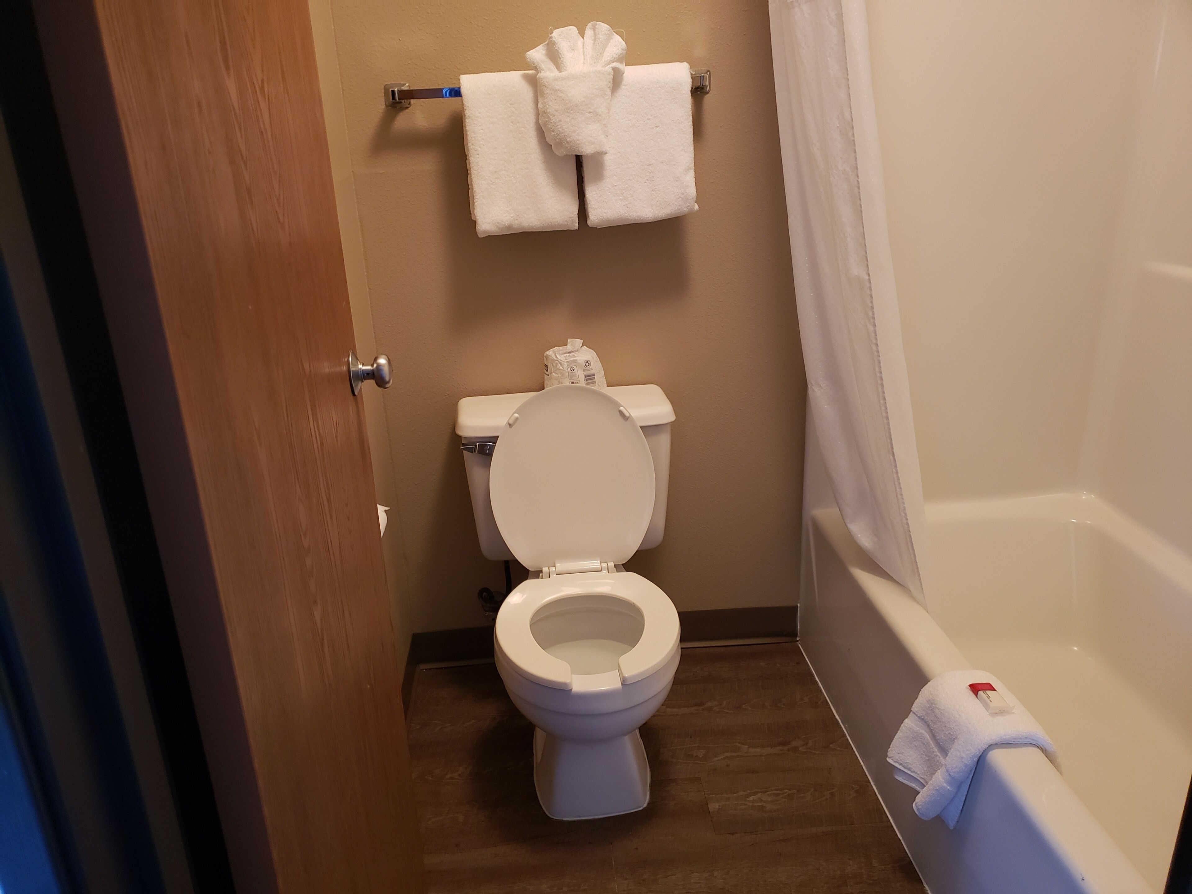 A bathroom with a toilet, a bathtub, and a towel rack with two towels.