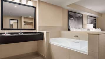 A modern bathroom with a large mirror, a bathtub, and a vanity with a sink.