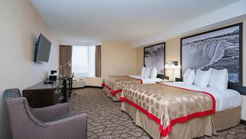 A hotel room with two beds, a desk, a chair, a TV, and a large window.