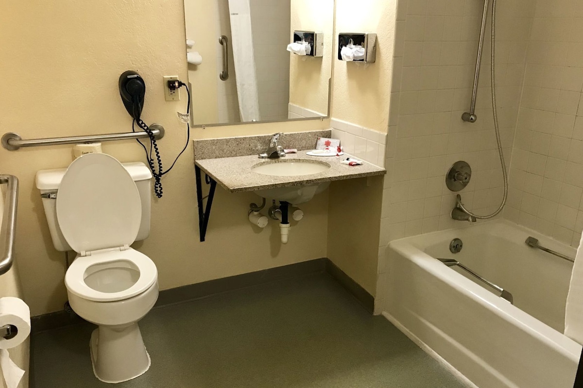 A bathroom with a toilet, sink, mirror, and bathtub.