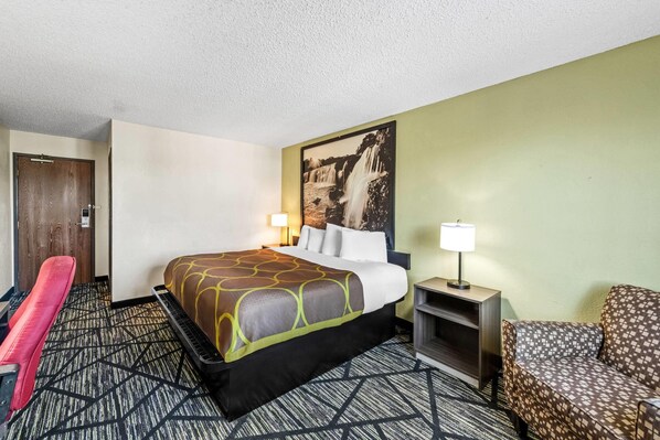 Una habitación de hotel con una cama, un escritorio, una silla y un cuadro en la pared.