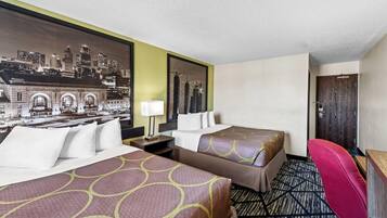 Quarto de hotel com duas camas, uma escrivaninha, uma cadeira e um mural com vista para a cidade.