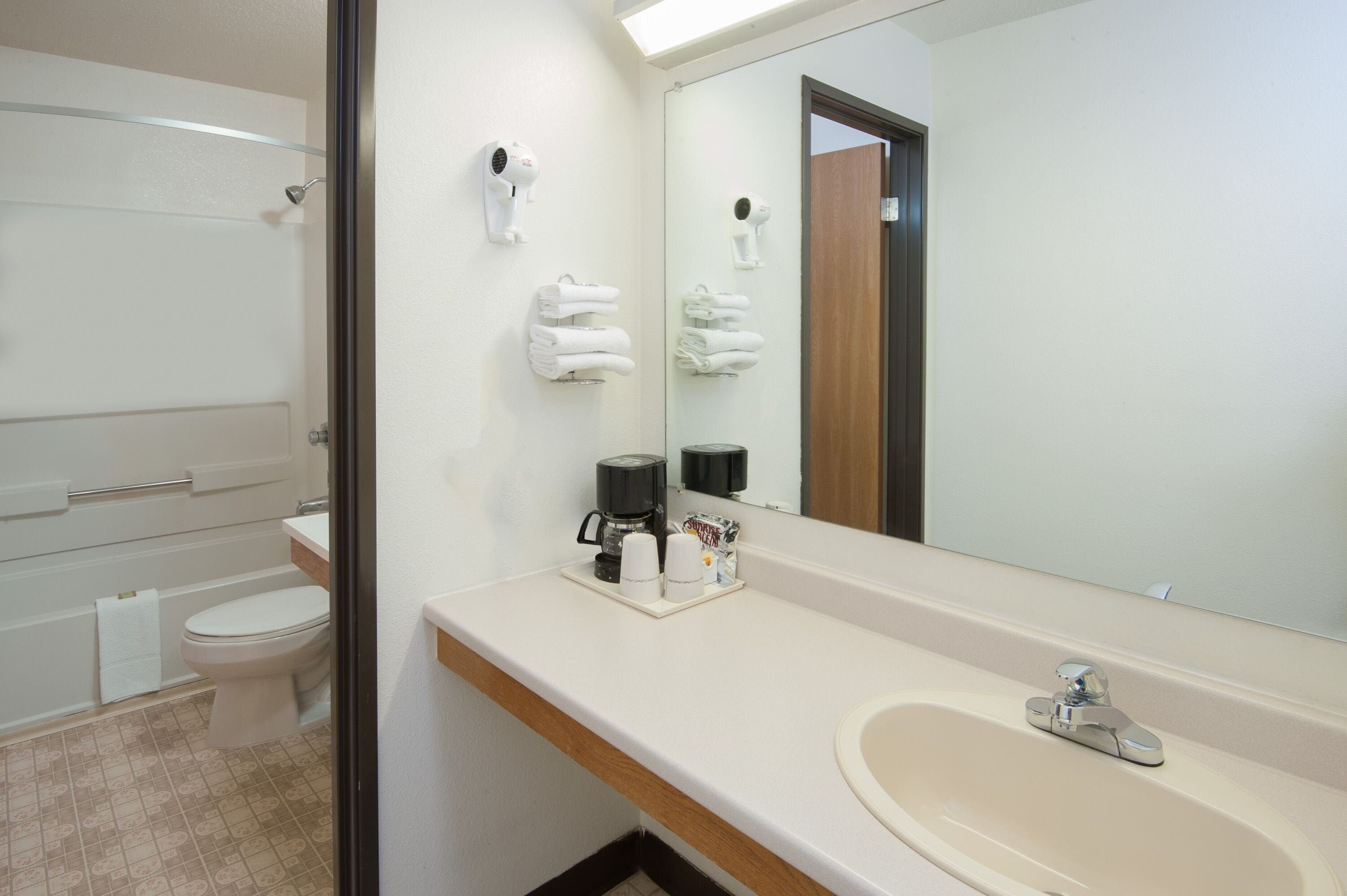 Un baño con inodoro, lavamanos, espejo y cabina de ducha.