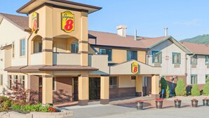 Un hotel Super 8 de estructura de dos pisos, con un llamativo letrero de 'Super 8' en la fachada y un área de entrada ajardinada con plantas en macetas.