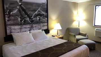 Une chambre d’hôtel avec un lit, une chaise, une lampe et un grand tableau encadré au mur.