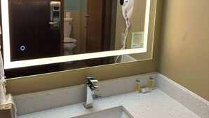 A bathroom with a modern sink, a hairdryer mounted on the wall, and toiletries on the counter. - Super 8 by Wyndham Perry IA (Perry)