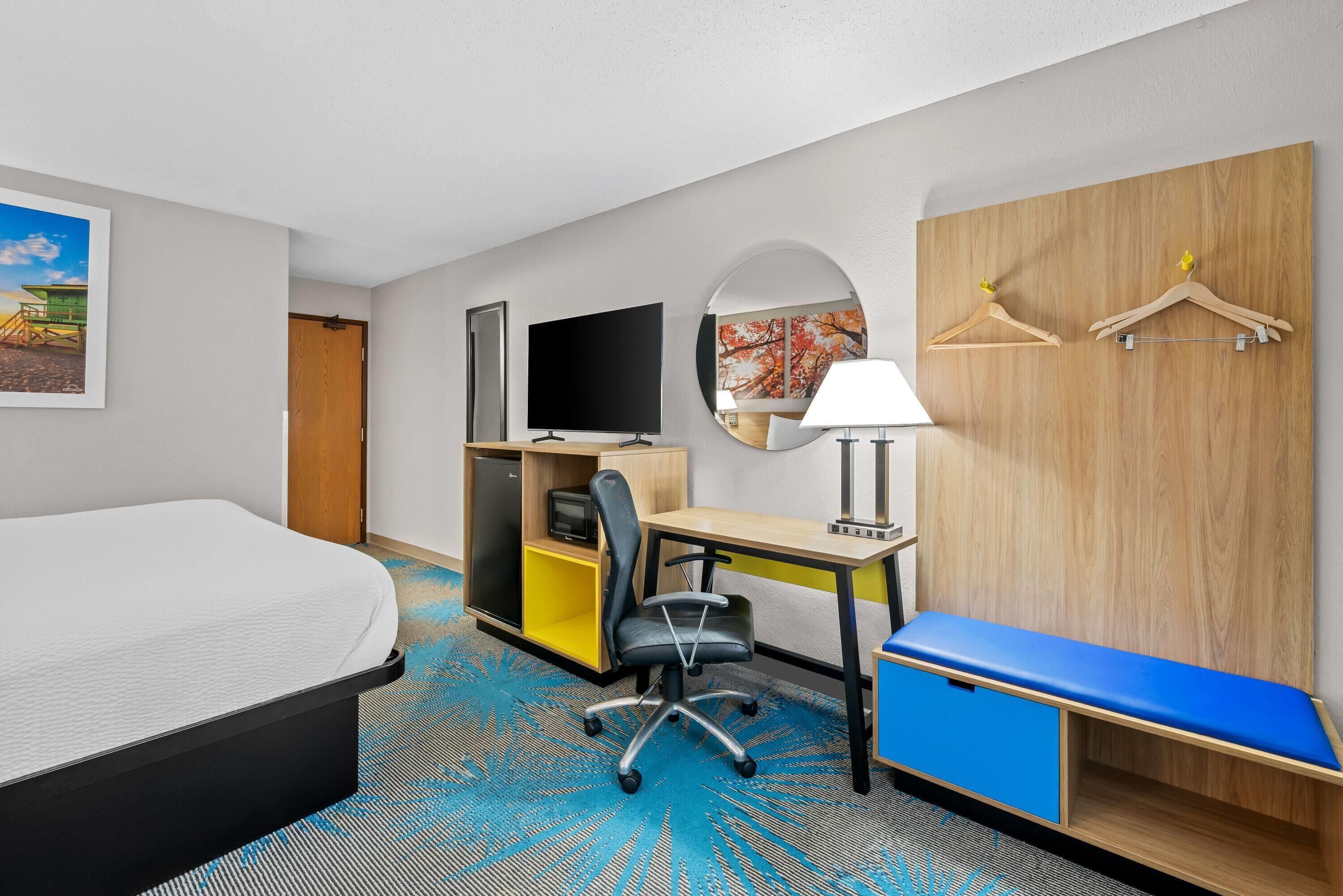 Een hotelkamer met een bed, bureau, stoel, televisie en een blauwe bank.