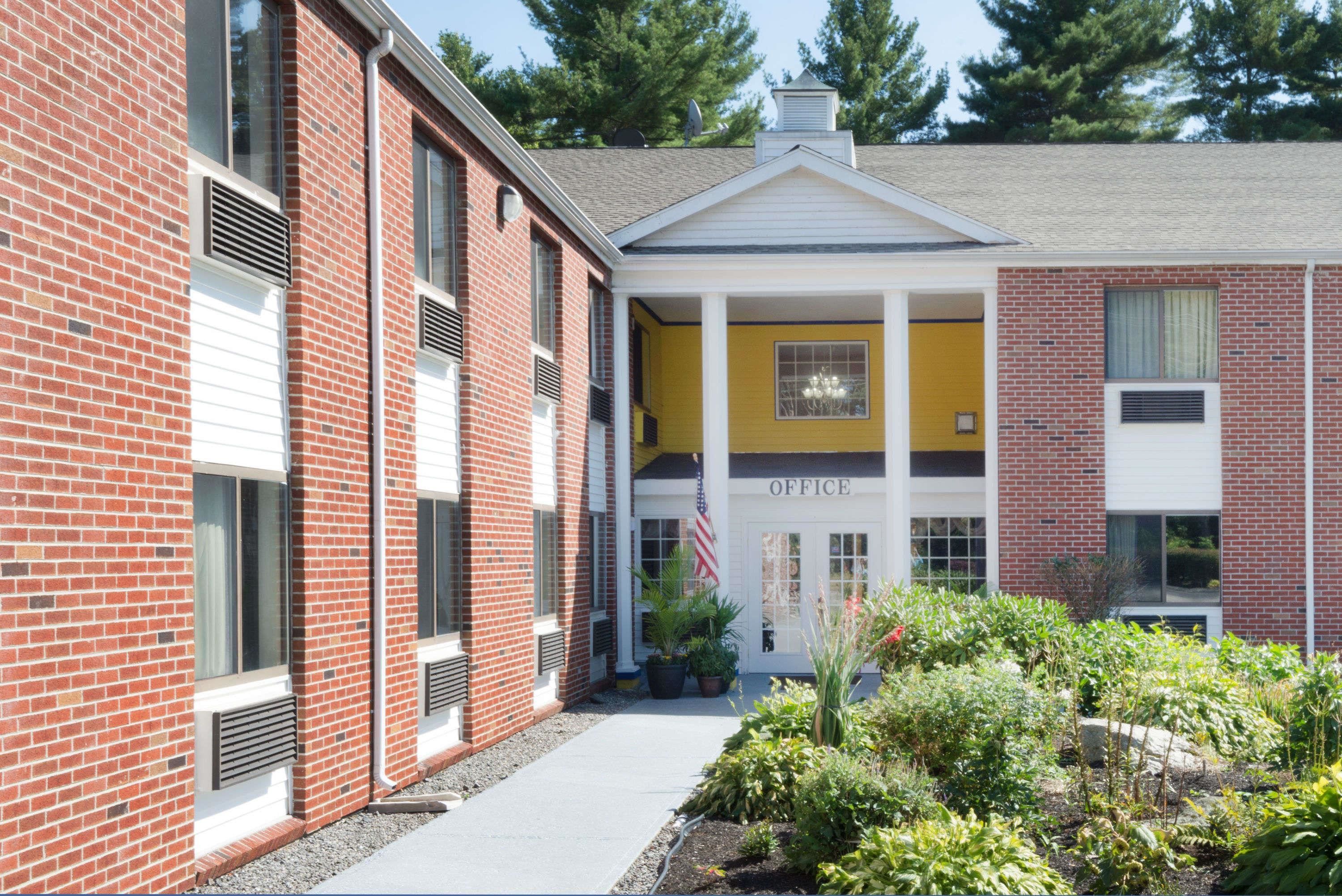 A two-story building with a brick facade, an American flag, and a sign labeled "OFFICE".
