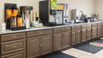 Una kitchenette con máquinas de café, un refrigerador y un microondas.
