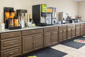 Uma cozinha compacta com máquinas de café, geladeira e micro-ondas.