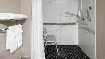 A shower with a glass door, a white towel rack, and a step stool.
