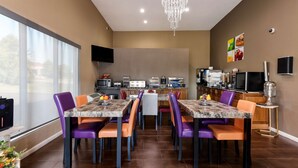 Una cocina moderna con comedor, que incluye una mesa de mármol, sillas moradas y anaranjadas, y un candelabro.