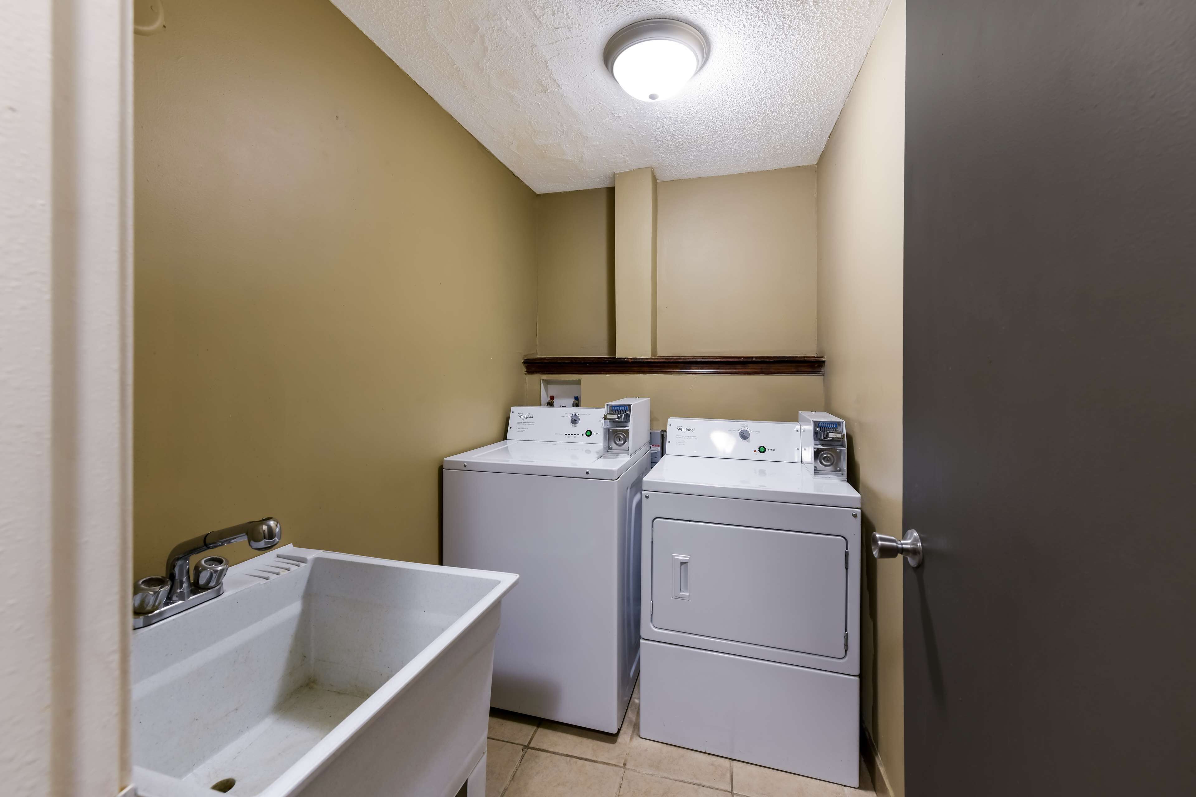 A compact laundry room with two front-loading washing machines and a sink.