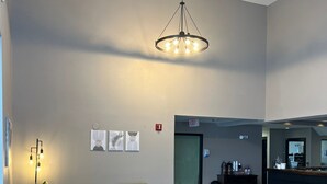 Amplia sala de estar con techo alto, un candelabro central y una recepción al fondo.