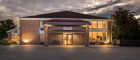 A modern building with a brick facade, large glass windows, and a covered entrance area.