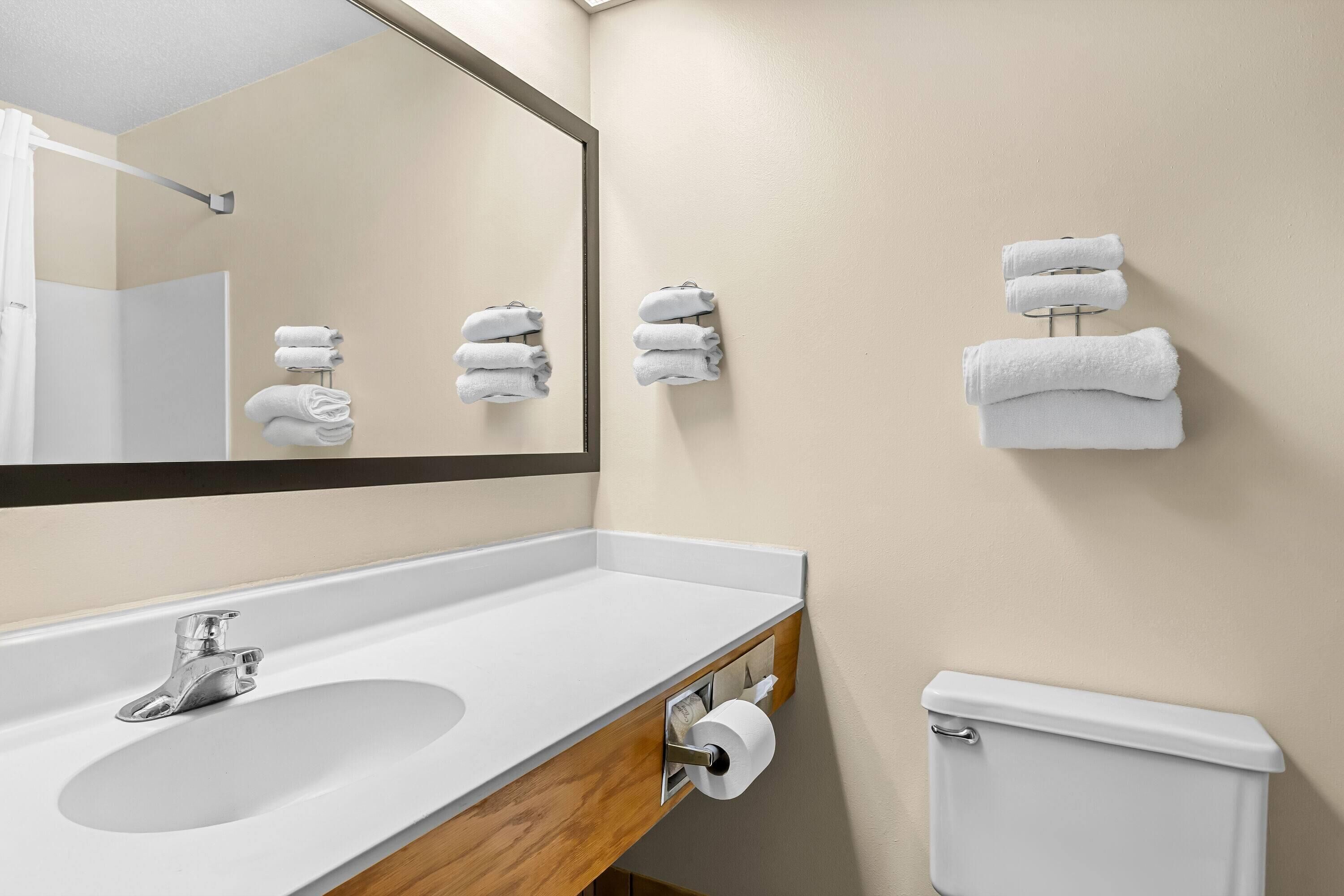 Een badkamer met een wastafel, spiegel, handdoekhouder en toilet.