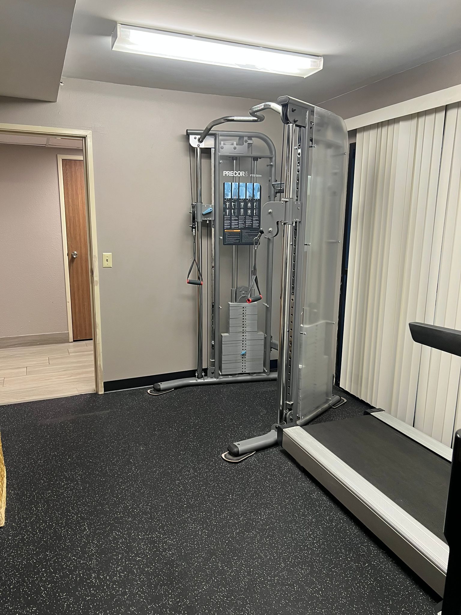 A gym with a pull-up bar, a step platform, and a wall-mounted exercise machine.