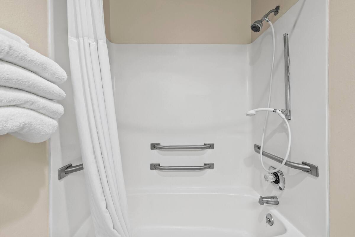 A bathroom with a bathtub, shower, and two towel racks.