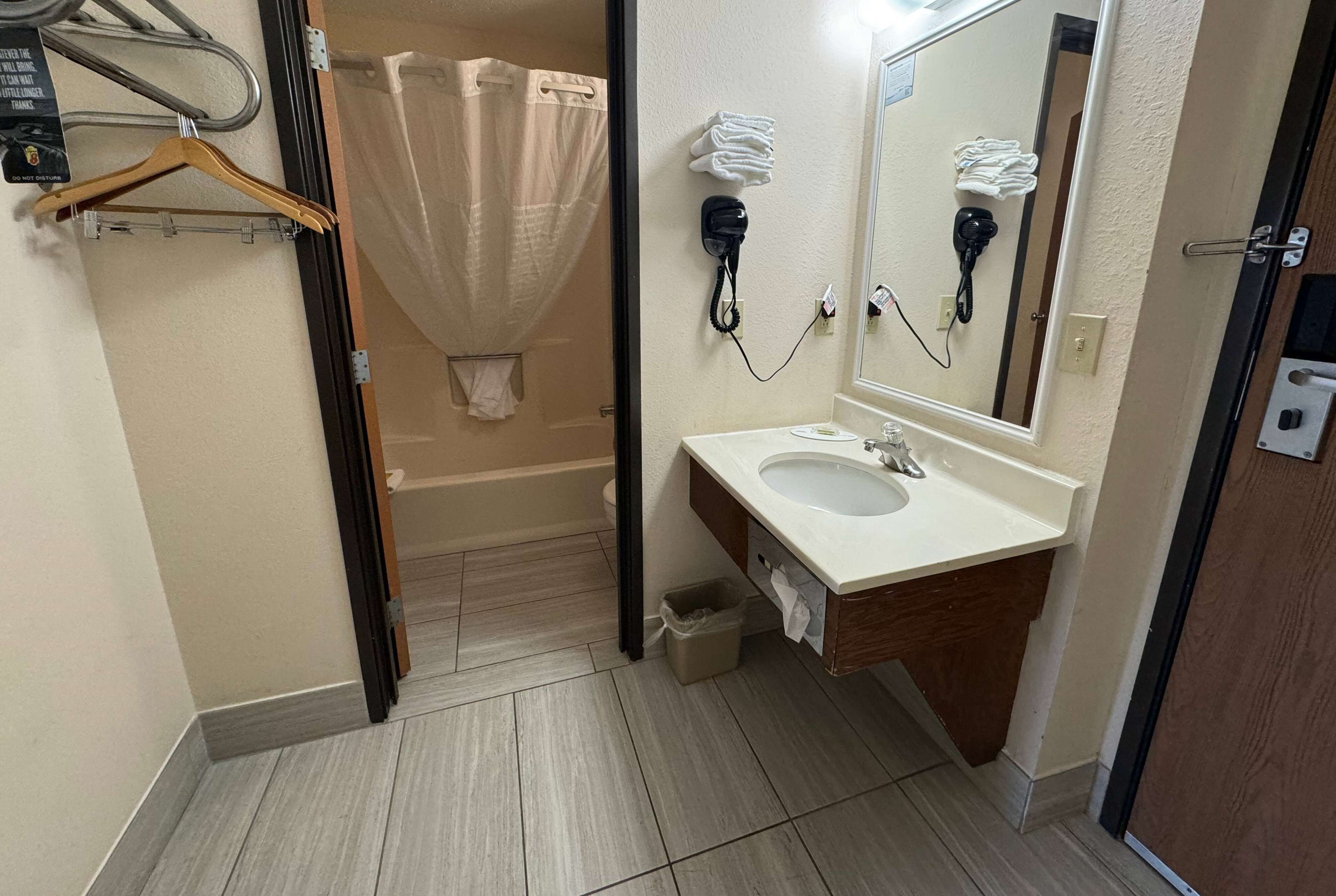 A bathroom with a sink, mirror, towel rack, and a shower curtain.