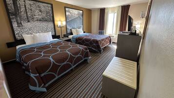 A hotel room with two beds, a desk, a TV, and artwork on the walls.