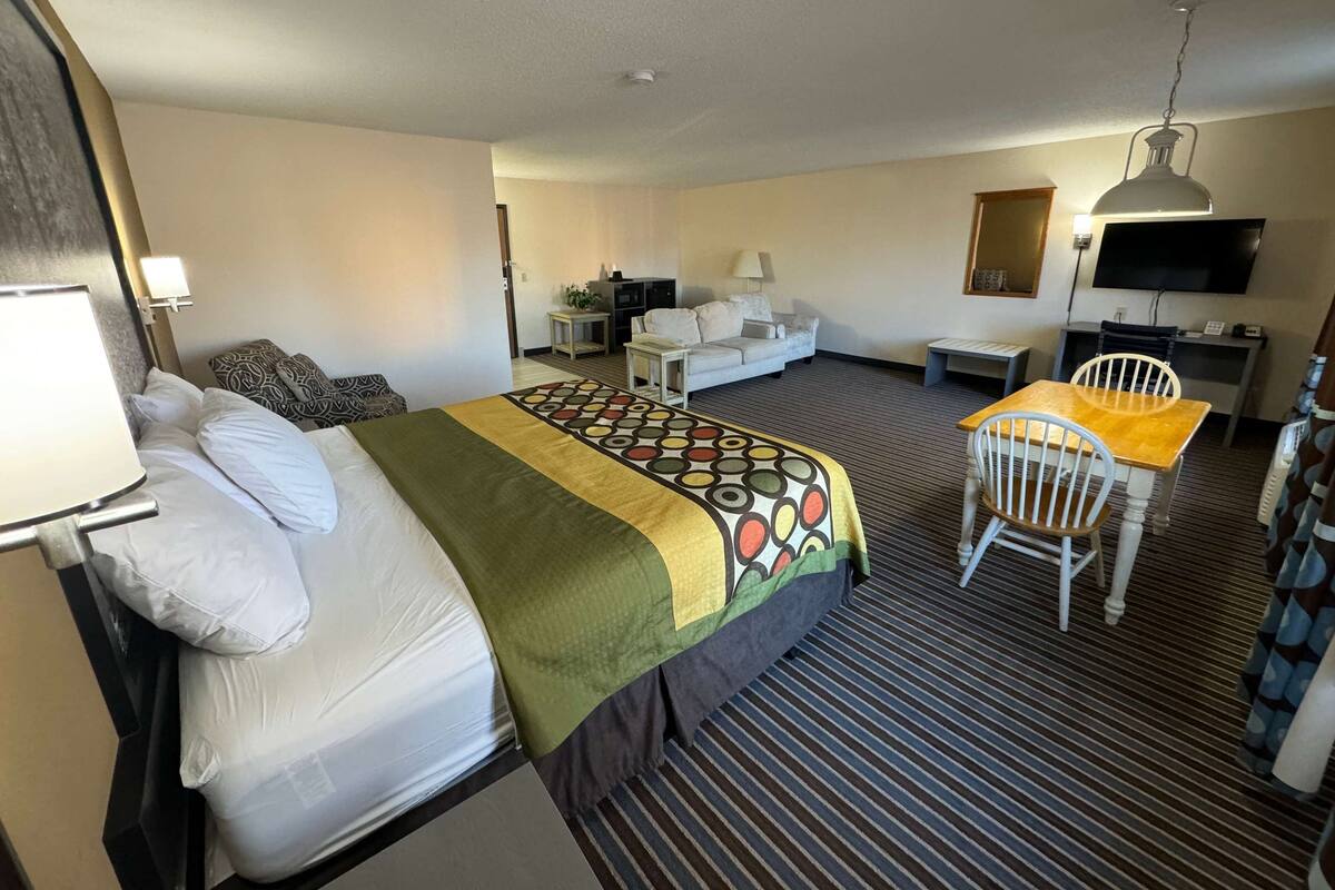 Ein Hotelzimmer mit Bett, Schreibtisch, Stuhl, Fernseher und Lampe.