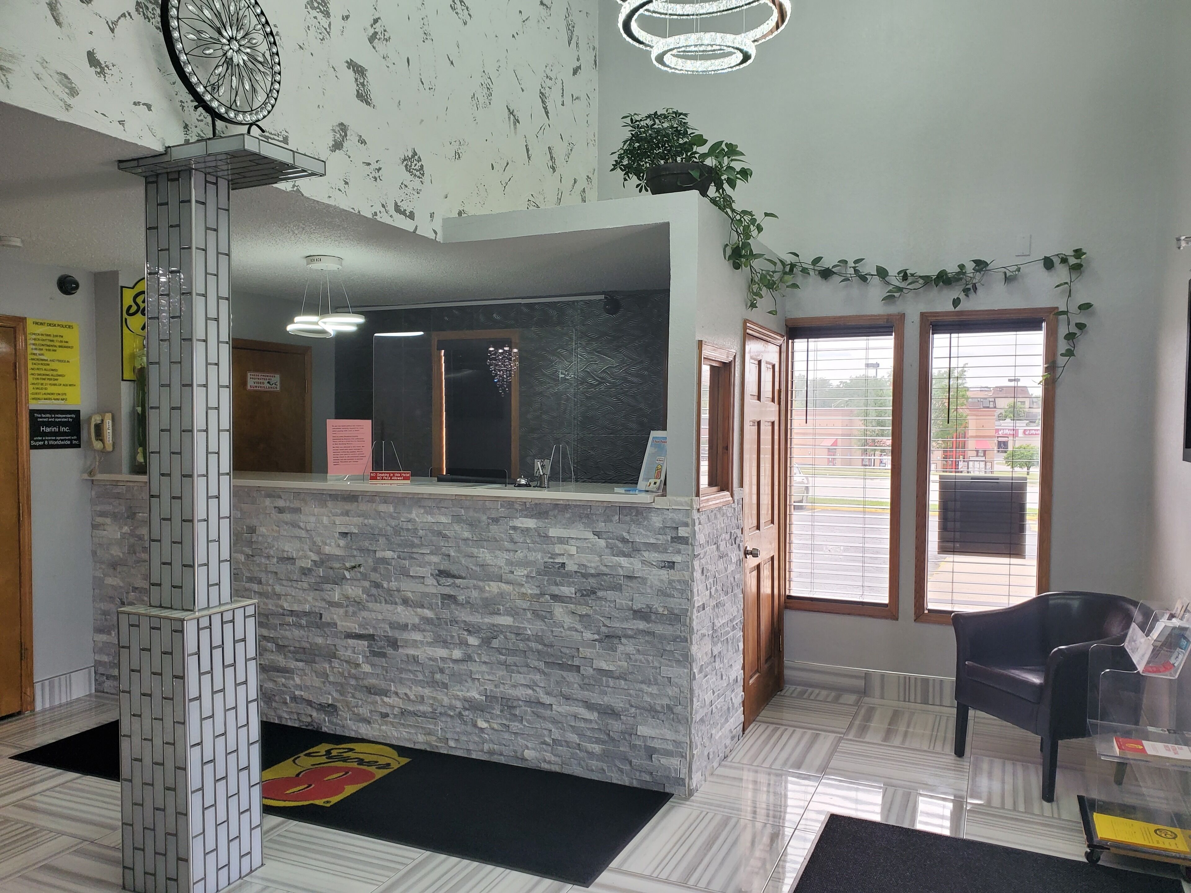 A reception area with a stone counter, a modern chandelier, and a view of the outside through a glass door.