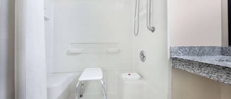 A bathroom with a shower, a toilet, and a small step stool.